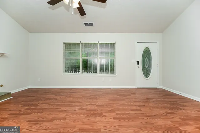 a view of an empty room with wooden floor and a fireplace