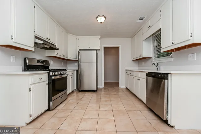 a kitchen with a white cabinets a refrigerator and a stove