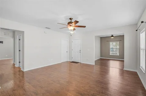 a view of an empty room with window and wooden floor
