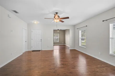 a view of an empty room with window and wooden floor
