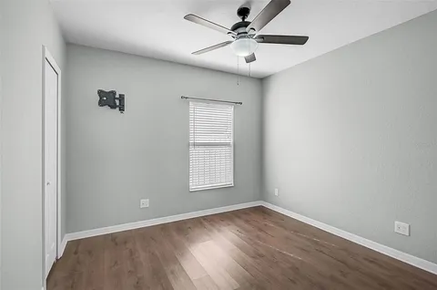 an empty room with wooden floor fan and windows
