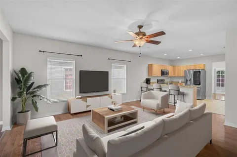 a living room with furniture a ceiling fan and a flat screen tv