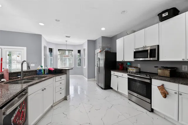 a kitchen with stainless steel appliances granite countertop a sink and a stove