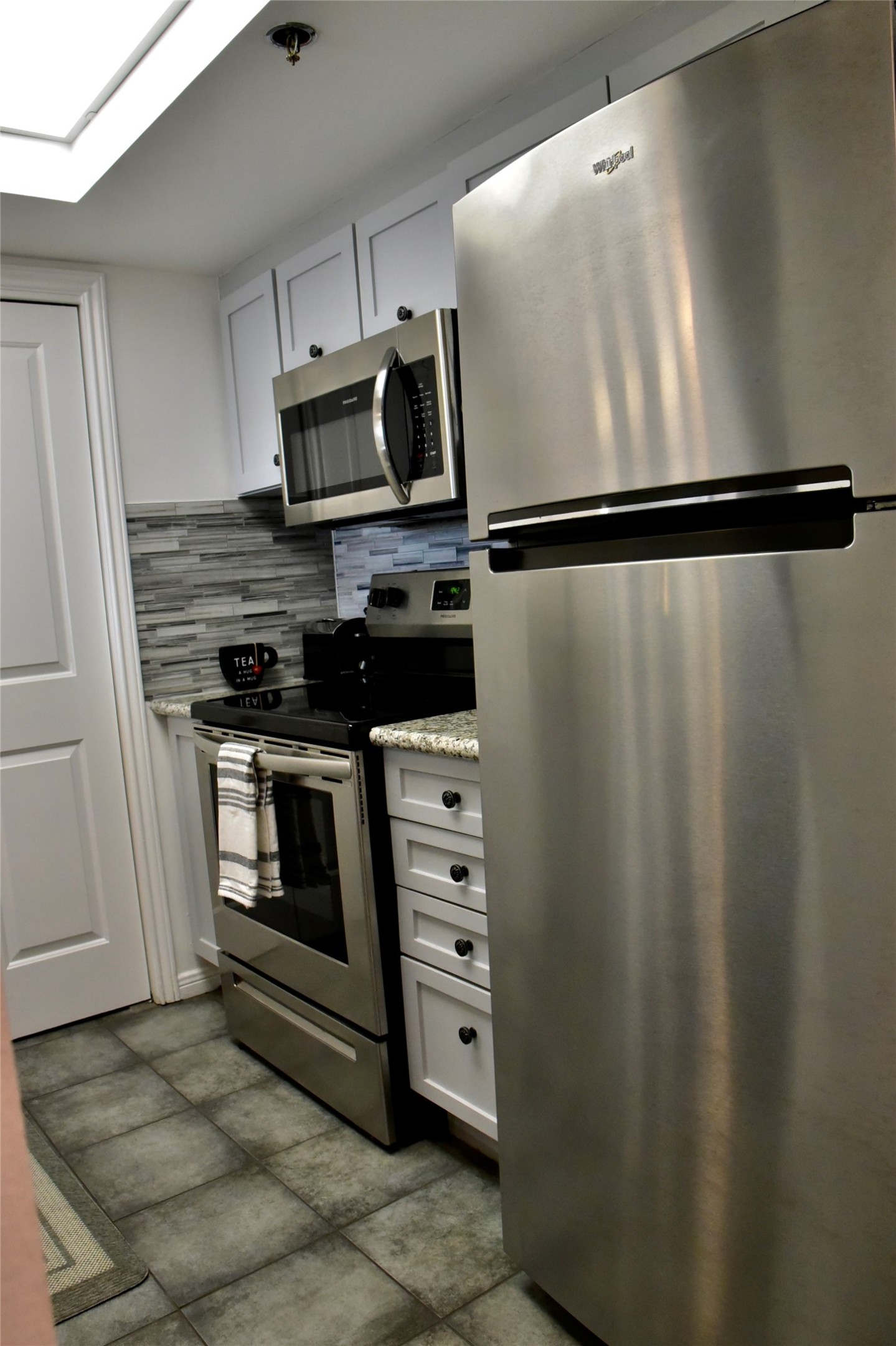 3525 Sage Road, Unit 701 Houston, TX 77056 - Photo 9 of 48 Modern kitchen featuring stainless steel appliances, white cabinetry, and a stylish backsplash.