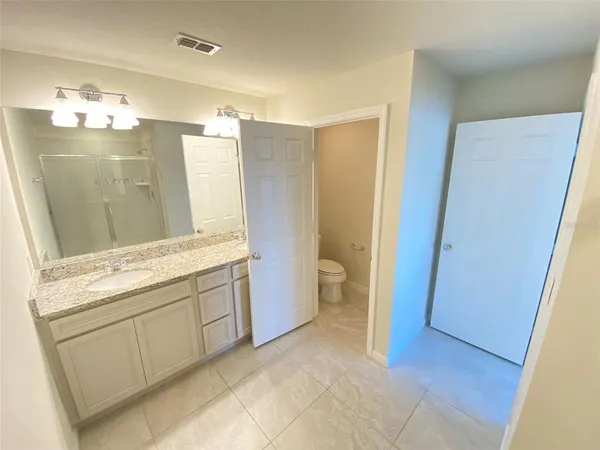 a spacious bathroom with a granite countertop sink a mirror and a bathtub