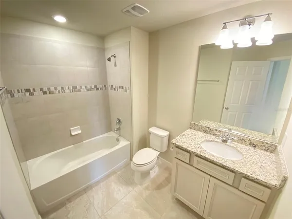 a bathroom with a granite countertop sink a toilet and shower