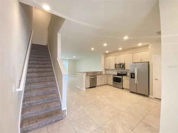 a view of kitchen with stainless steel appliances kitchen island wooden cabinets and entryway