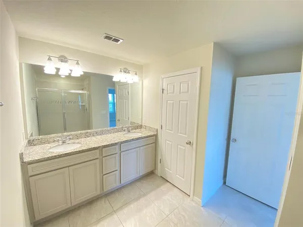 a spacious bathroom with a granite countertop sink a mirror and a shower