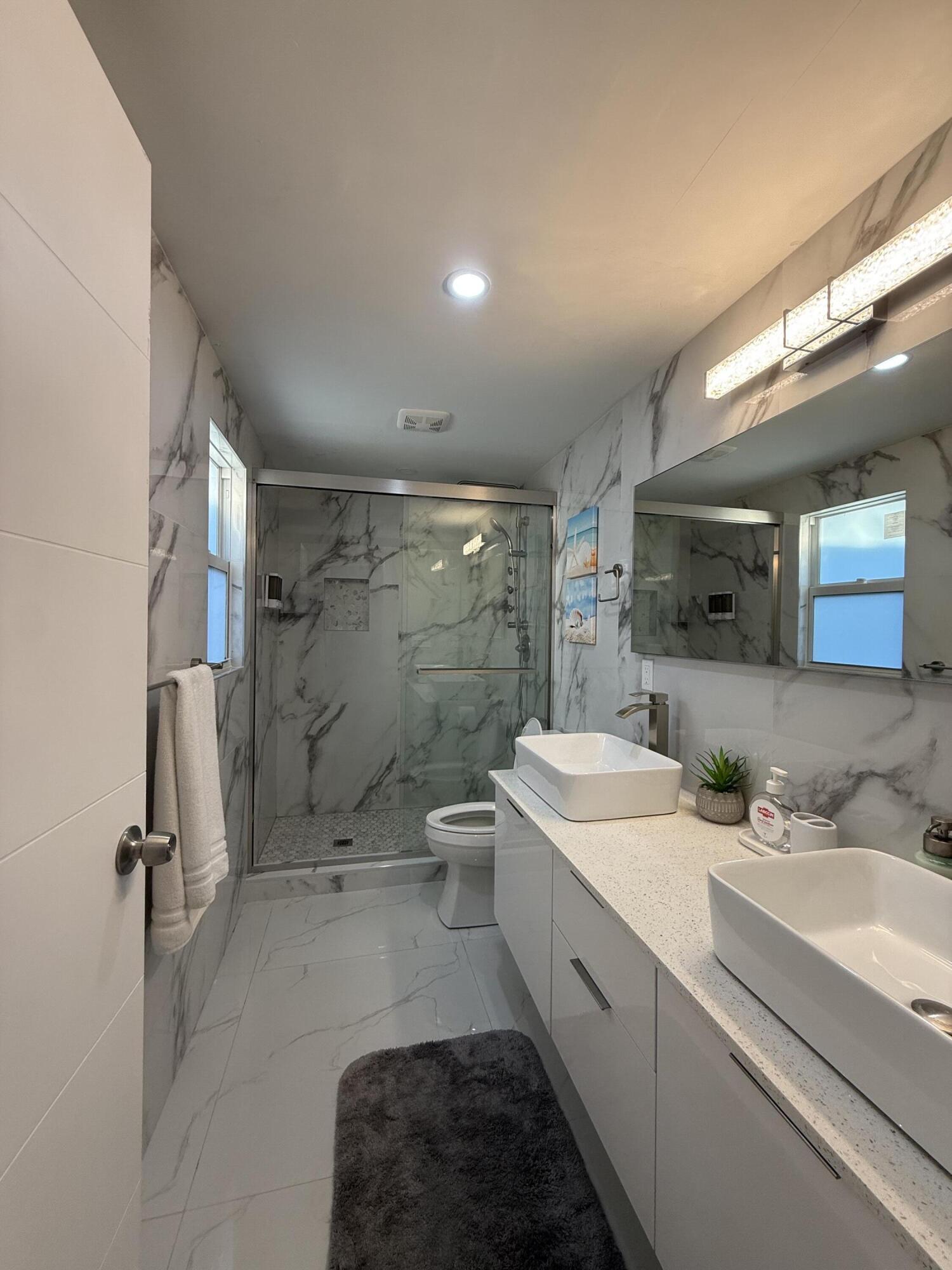 255 Glouchester Street Boca Raton, FL 33487 - Photo 7 of 11 a bathroom with a double vanity sink toilet mirror and shower