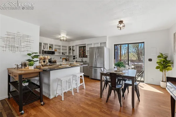 a kitchen with stainless steel appliances kitchen island granite countertop a table chairs stove and refrigerator
