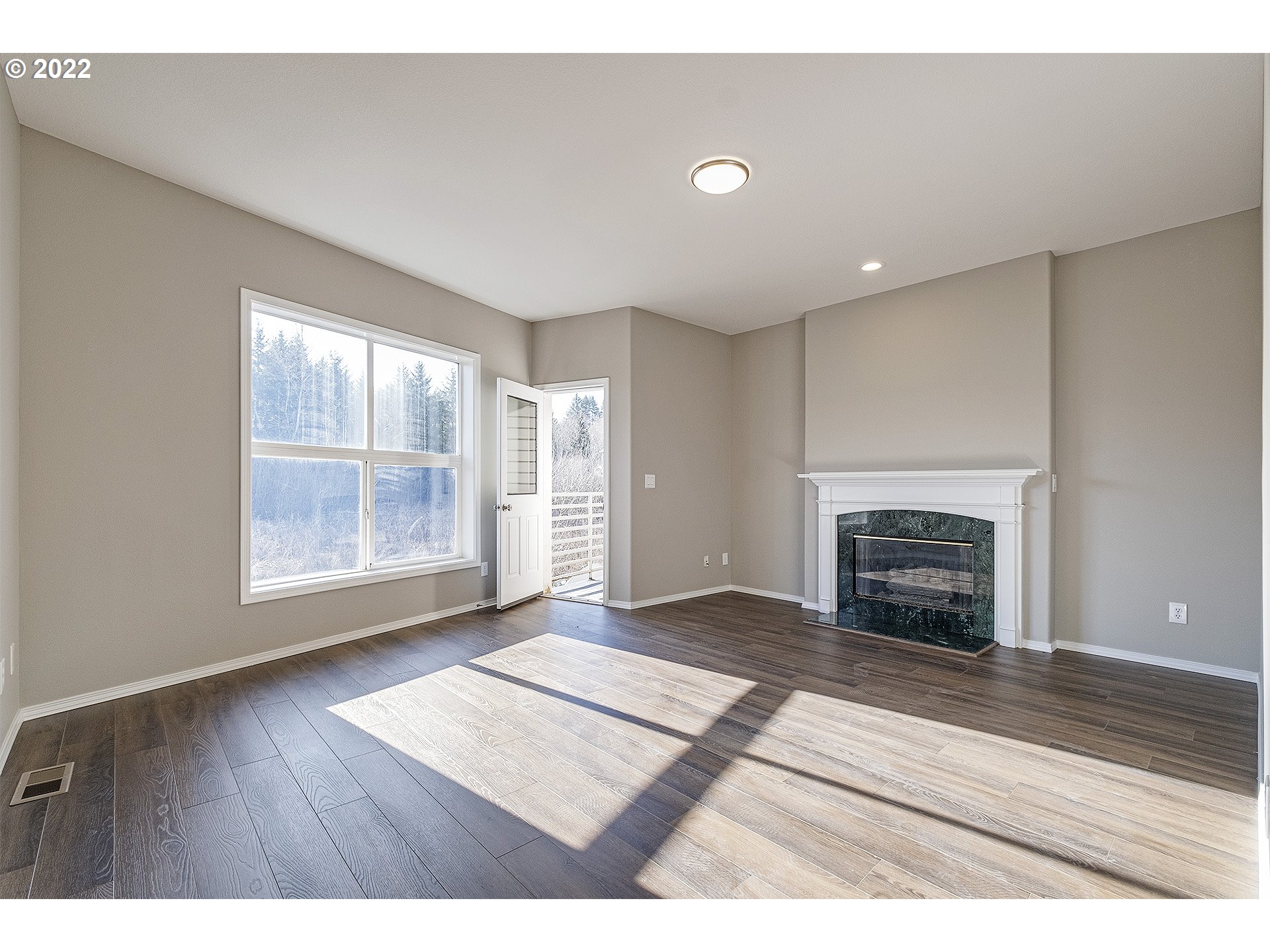 15718 Southwest Flagstone Drive Beaverton, OR 97007 - Photo 3 of 32 a view of an empty room with wooden floor fireplace and a window