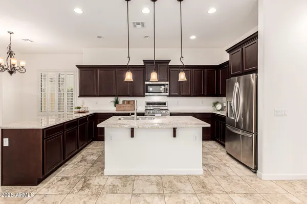 a kitchen with kitchen island granite countertop a sink dishwasher stove top oven and refrigerator with wooden floor