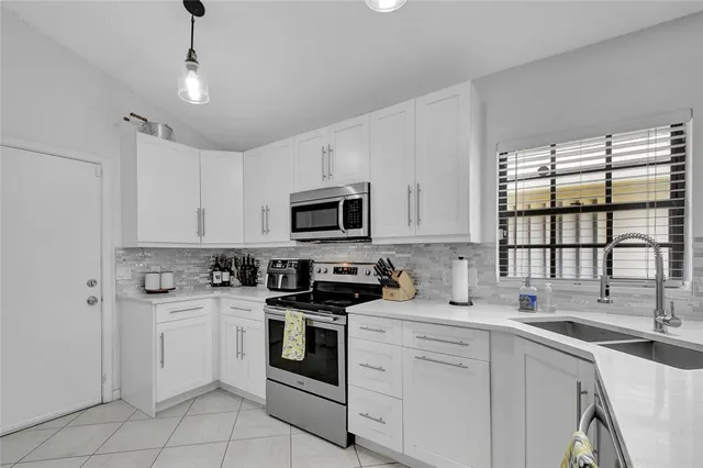 a kitchen with white cabinets appliances a sink and a window