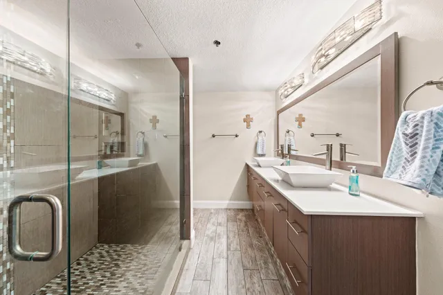 a bathroom with a double vanity sink a toilet a mirror and shower