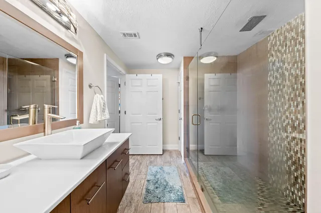 a spacious bathroom with a granite countertop sink a mirror and shower