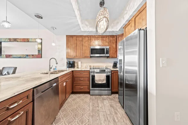 a kitchen with stainless steel appliances granite countertop a refrigerator a sink a stove top oven and a dishwasher