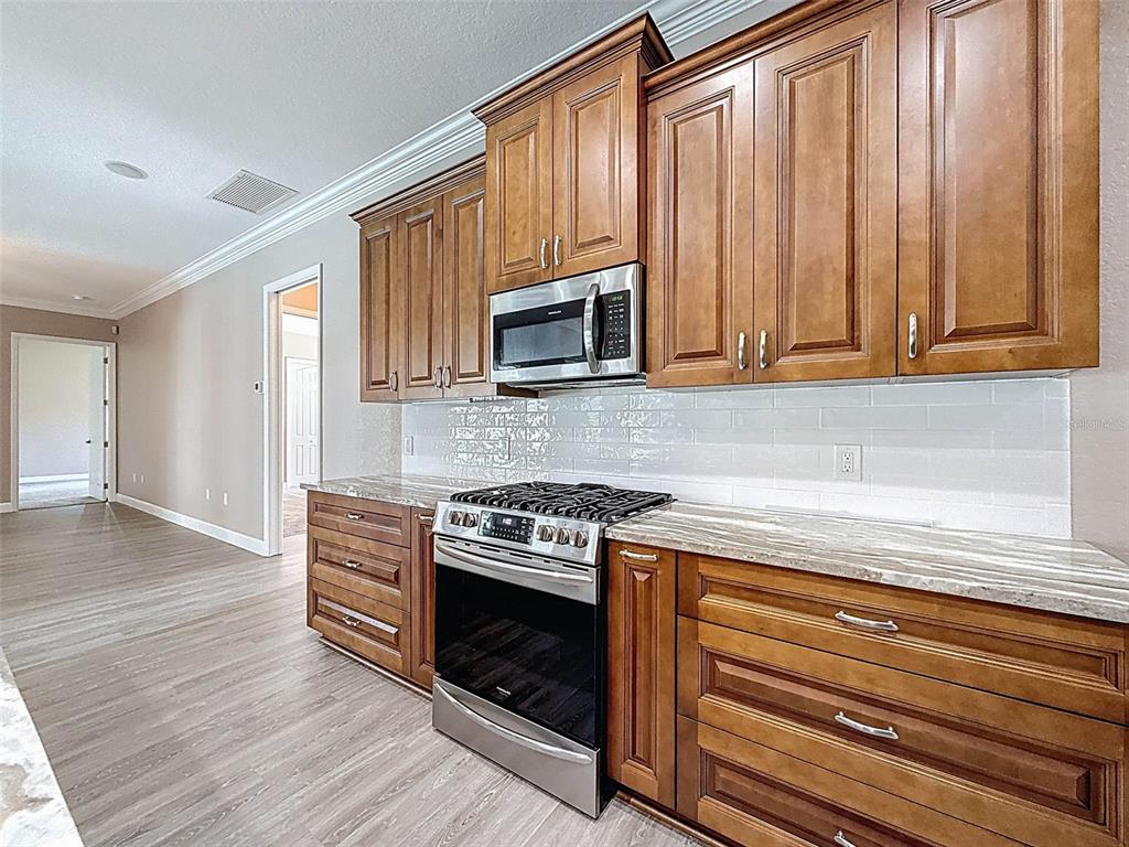 11235 Warm Wind Way Weeki Wachee, FL 34613 - Photo 25 of 93 a kitchen with wooden cabinets and a stove top oven