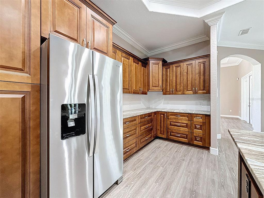 11235 Warm Wind Way Weeki Wachee, FL 34613 - Photo 27 of 93 a kitchen with stainless steel appliances granite countertop a refrigerator a stove and a wooden cabinets