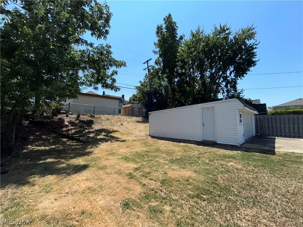 9316 Alexander Road Garfield Heights, OH 44125 - Photo 25 of 27 Detached garage with siding exterior and access door, concrete driveway, and chain-link fencing