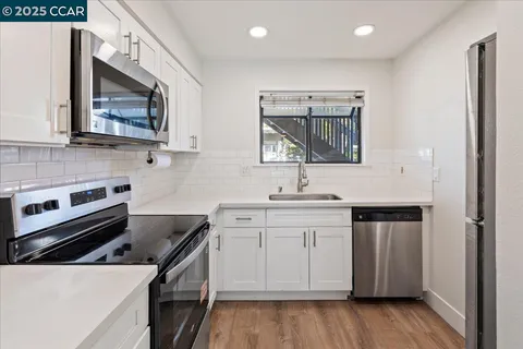 a kitchen with stainless steel appliances granite countertop white cabinets a sink and a stove