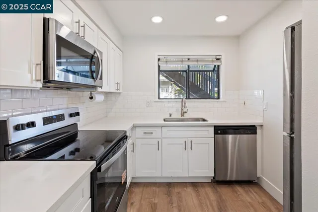 a kitchen with stainless steel appliances granite countertop white cabinets a sink and a stove