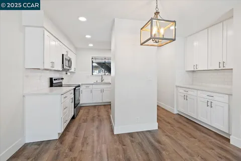 a living room with furniture a chandelier and a dining table with wooden floor