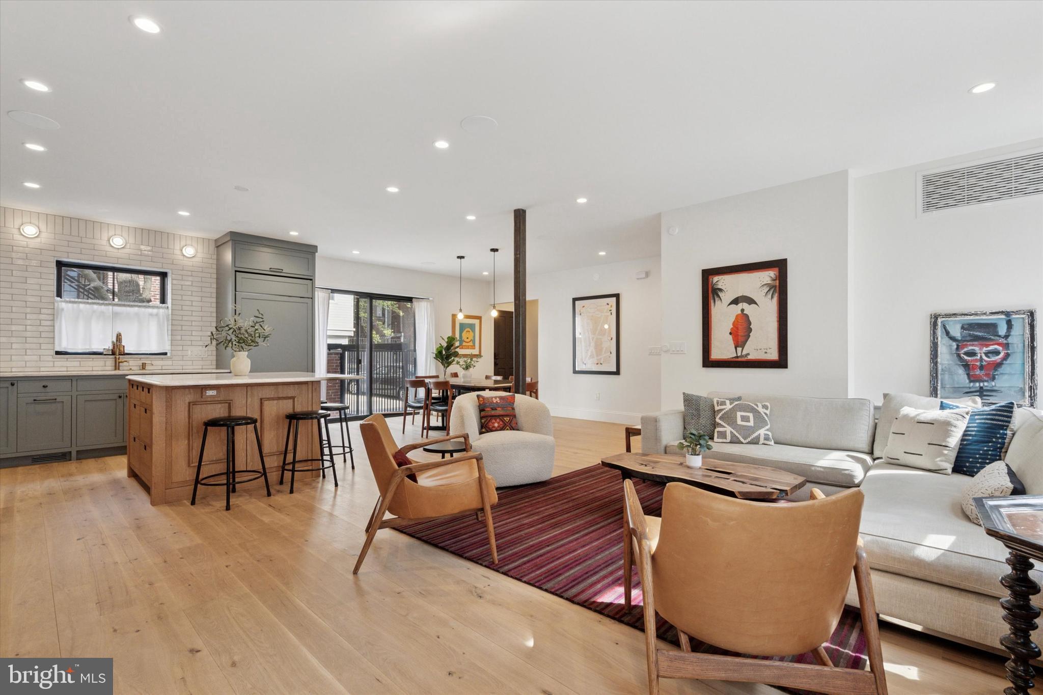 a living room with couches and kitchen view with wooden floor