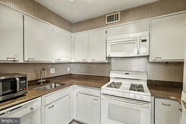 a kitchen with stainless steel appliances granite countertop white cabinets and a stove a oven with white countertops