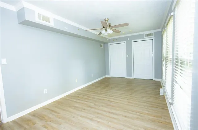 a view of empty room with wooden floor and fan