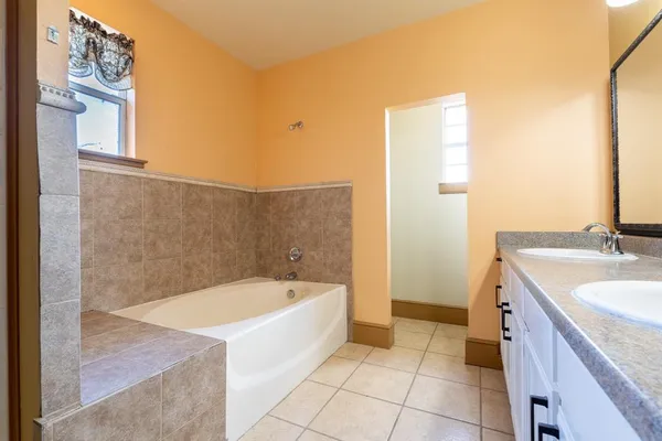 a spacious bathroom with a tub sink and mirror