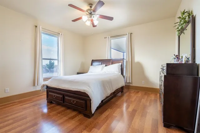 a view of a hallway with wooden floor and a bathroom
