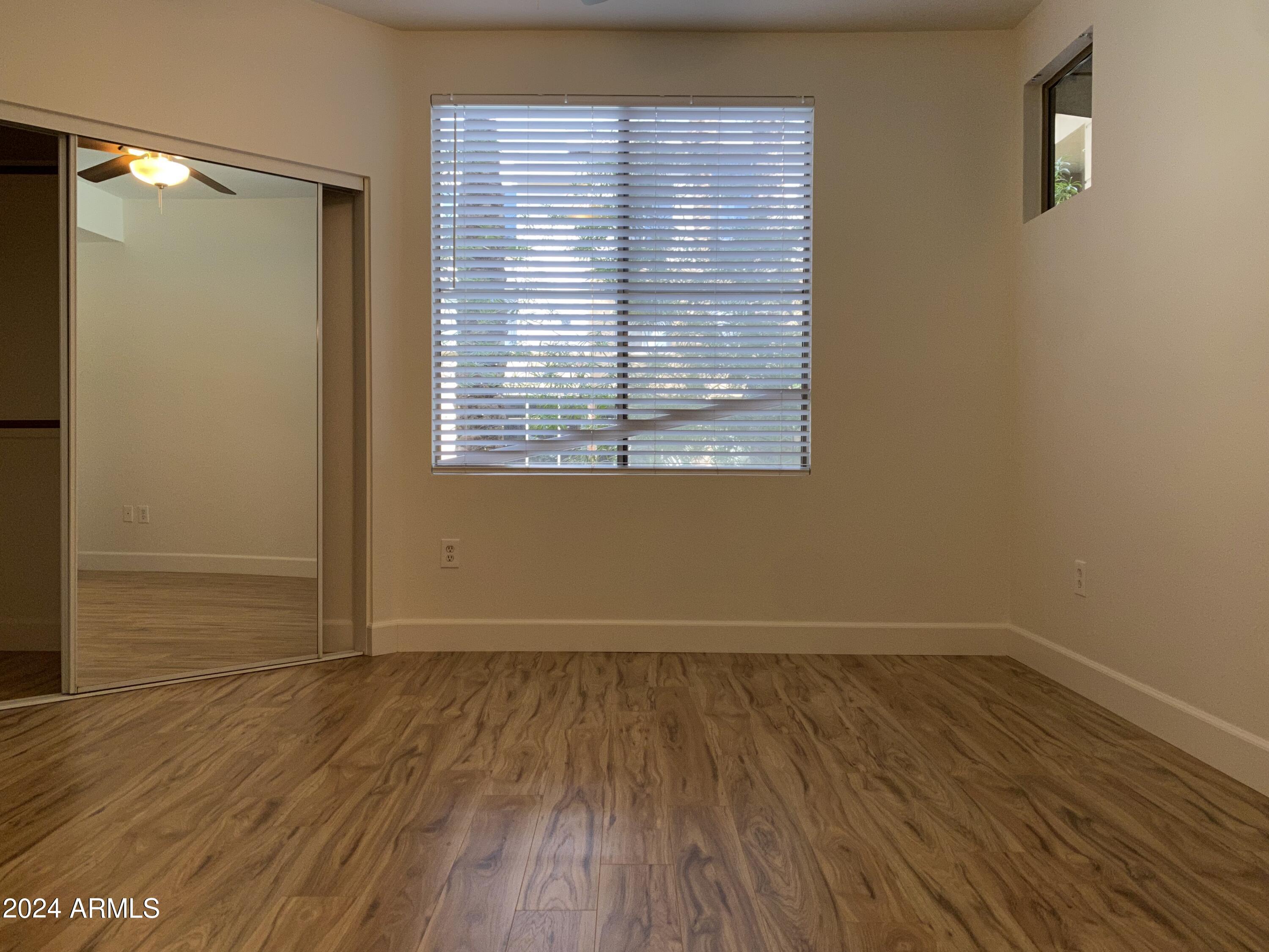 1701 East Colter Street, Unit 215 Phoenix, AZ 85016 - Photo 8 of 28 an empty room with wooden floor and windows