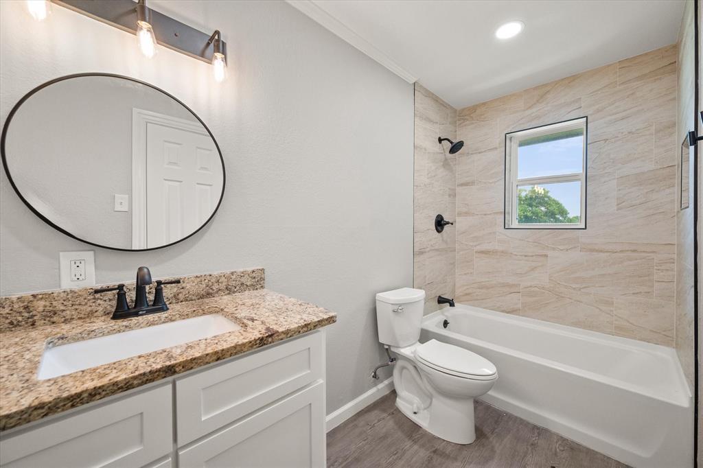 1009 North Spikes Road Corsicana, TX 75110 - Photo 13 of 31 a bathroom with a granite countertop toilet a sink and a mirror