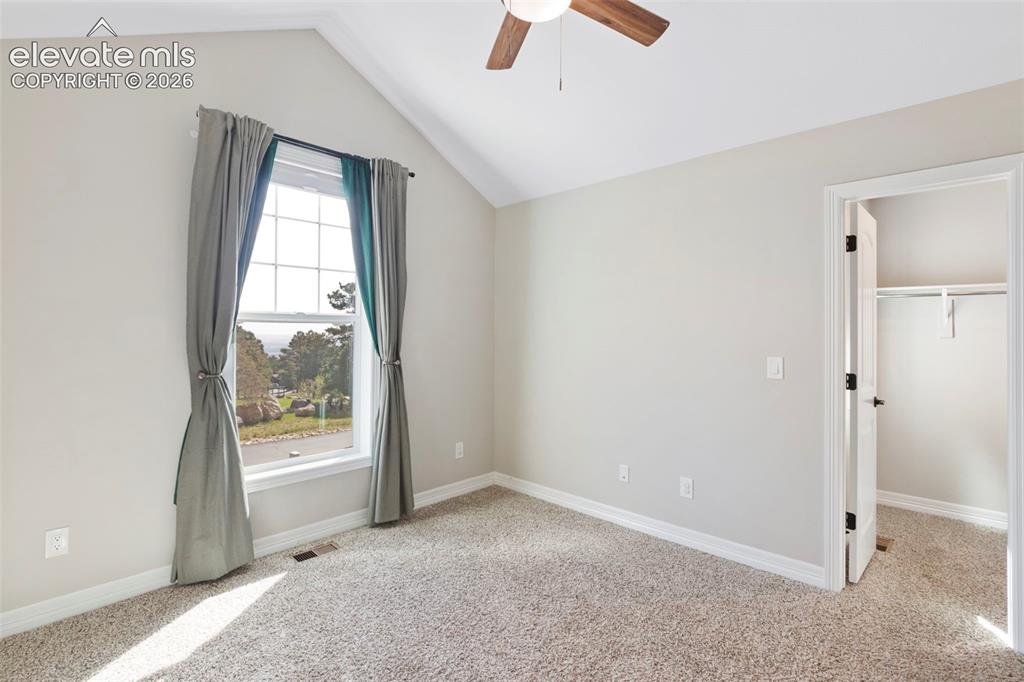 5375 Old Star Ranch View Colorado Springs, CO 80906 - Photo 19 of 47 Vaulted ceiling room featuring a large multi-pane window, neutral-toned carpeting, a wood-finish ceiling fan, and a built-in closet with shelving and hanging rod