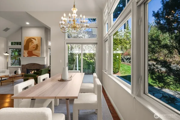 a view of a dining room with furniture a chandelier and large windows