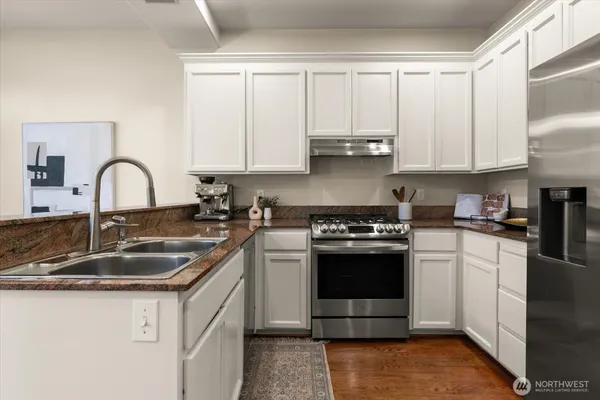 a kitchen with stainless steel appliances granite countertop a sink a stove and a refrigerator