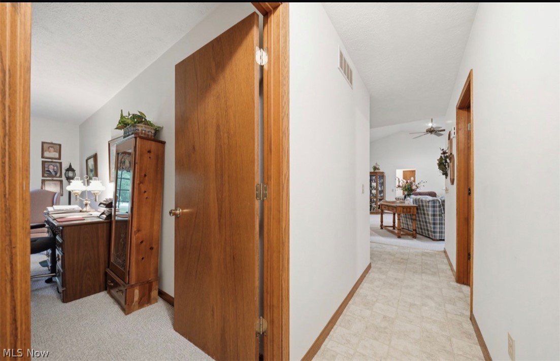 3556 Lake Road Conneaut, OH 44030 - Photo 11 of 39 Hallway with wood-finish trim and doors, leading to a living area with a vaulted ceiling and ceiling fan