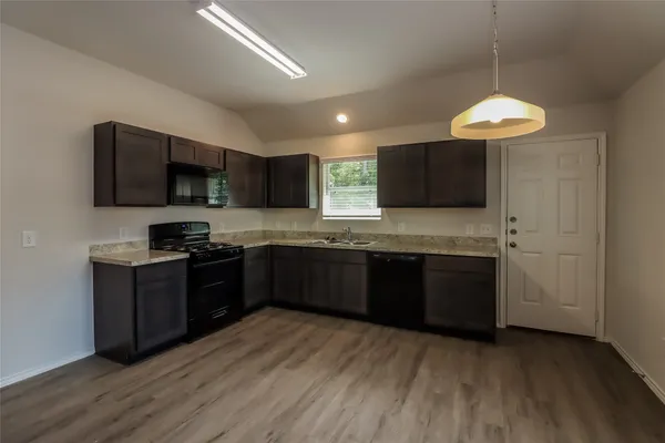 a kitchen with granite countertop a stove top oven a sink dishwasher and a microwave oven with wooden floor