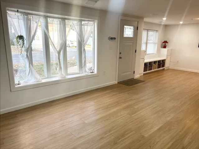 a view of an empty room with a window and wooden floor