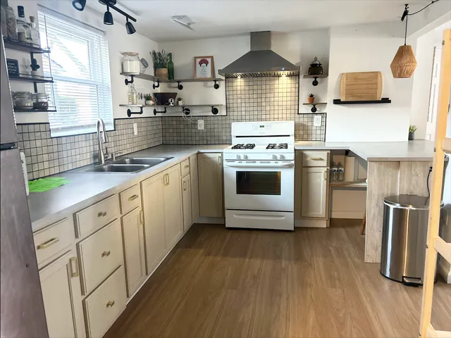 a kitchen with stainless steel appliances a sink a stove a refrigerator cabinets and wooden floor