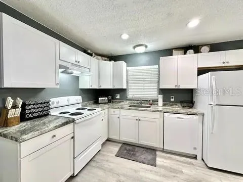 a kitchen with granite countertop appliances a sink and a refrigerator