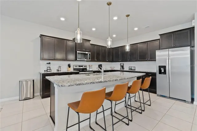 a kitchen with stainless steel appliances granite countertop a sink a stove a refrigerator and island with wooden floor