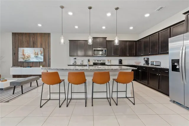 a kitchen with stainless steel appliances kitchen island granite countertop a refrigerator and a sink