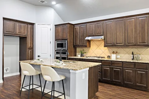 a kitchen with granite countertop a sink cabinets and wooden floor