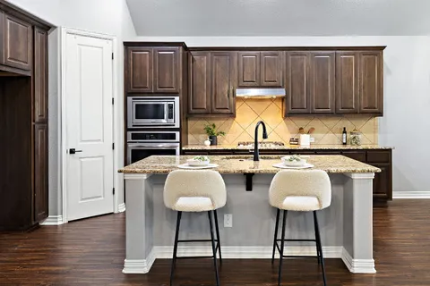a kitchen with stainless steel appliances a sink cabinets and wooden floor