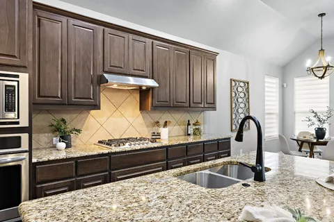 a kitchen with granite countertop a stove a sink and a microwave