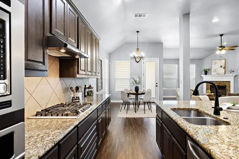 a kitchen with stainless steel appliances granite countertop a sink a stove and a wooden floors