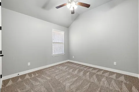 an empty room with a chandelier fan and windows