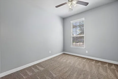 an empty room with a chandelier fan and windows