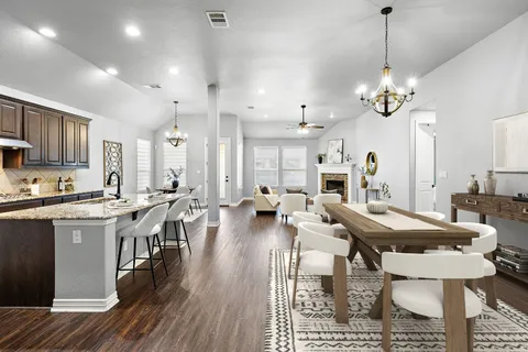 a very nice looking dining room with kitchen island stainless steel appliances furniture a fireplace a rug kitchen view and living room view